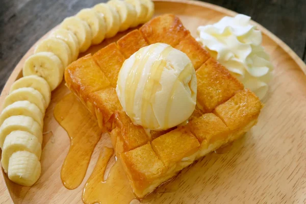 Honey Toast with Banana and Vanilla Ice Cream on Wooden Salver. Close Up Bread Buttered Toast with Whipped Cream Dessert on Wood Dish Background Great for Any Use.