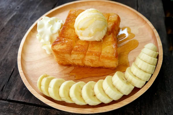 蜂蜜烤面包与香蕉和香草冰淇淋在木托盘 在木碟背景下 用奶油甜点把面包涂上黄油土司 — 图库照片