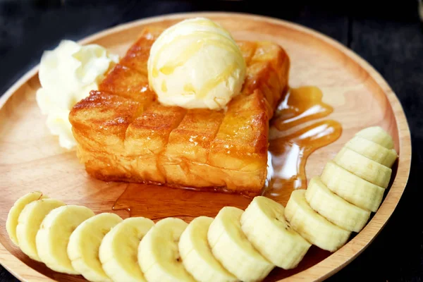蜂蜜烤面包与香蕉和香草冰淇淋在木托盘 在木碟背景下 用奶油甜点把面包涂上黄油土司 — 图库照片