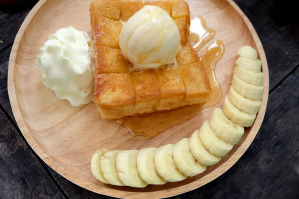 Honey Toast with Banana and Vanilla Ice Cream on Wooden Salver. Close Up Bread Buttered Toast with Whipped Cream Dessert on Wood Dish Background Great for Any Use.