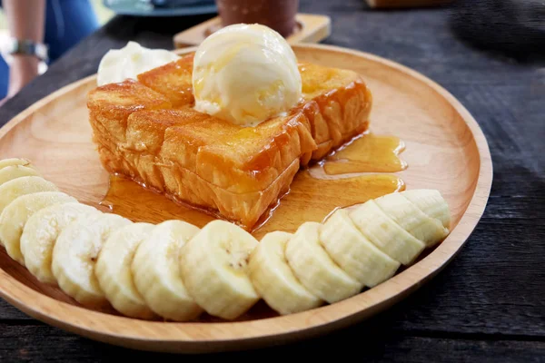 Honey Toast with Banana and Vanilla Ice Cream on Wooden Salver. Close Up Bread Buttered Toast with Whipped Cream Dessert on Wood Dish Background Great for Any Use.