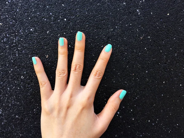 Green Manicure Nail. Beautiful Females Hand Nails Polish on the Concrete Wall Background