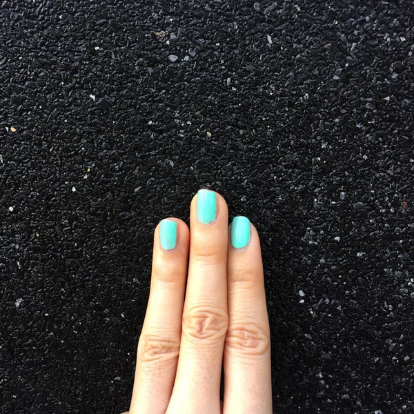 Green Manicure Nail. Beautiful Females Hand Nails Polish on the Concrete Wall Background