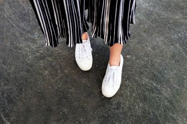 Beyaz spor ayakkabı ayakkabı. Kadın bacaklar beyaz spor ayakkabı ve pantolon üzerine beton Street arka plan büyük herhangi bir kullanım için..