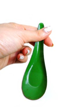 Kadın el manikürlü granit ile bir kaşık tutan çiviler. Beyaz zemin üzerine yeşil çinko kaşık kadar kapatın