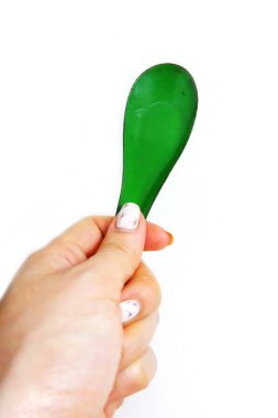 Kadın el manikürlü granit ile bir kaşık tutan çiviler. Beyaz zemin üzerine yeşil çinko kaşık kadar kapatın