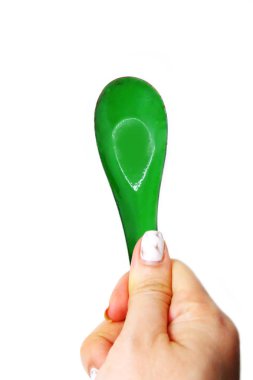 Kadın el manikürlü granit ile bir kaşık tutan çiviler. Beyaz zemin üzerine yeşil çinko kaşık kadar kapatın