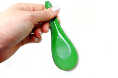 Kadın el manikürlü granit ile bir kaşık tutan çiviler. Beyaz zemin üzerine yeşil çinko kaşık kadar kapatın