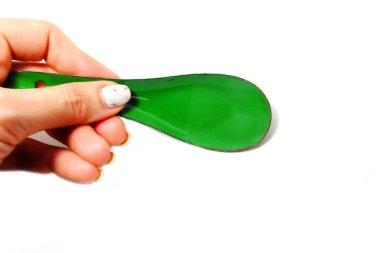 Kadın el manikürlü granit ile bir kaşık tutan çiviler. Beyaz zemin üzerine yeşil çinko kaşık kadar kapatın