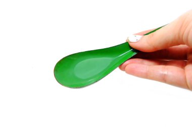 Kadın el manikürlü granit ile bir kaşık tutan çiviler. Beyaz zemin üzerine yeşil çinko kaşık kadar kapatın