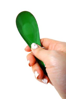 Kadın el manikürlü granit ile bir kaşık tutan çiviler. Beyaz zemin üzerine yeşil çinko kaşık kadar kapatın