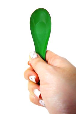Kadın el manikürlü granit ile bir kaşık tutan çiviler. Beyaz zemin üzerine yeşil çinko kaşık kadar kapatın
