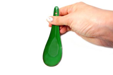 Kadın el manikürlü granit ile bir kaşık tutan çiviler. Beyaz zemin üzerine yeşil çinko kaşık kadar kapatın