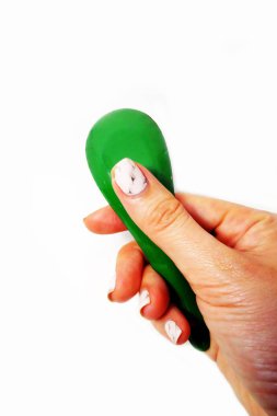 Kadın el manikürlü granit ile bir kaşık tutan çiviler. Beyaz zemin üzerine yeşil çinko kaşık kadar kapatın