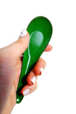 Kadın el manikürlü granit ile bir kaşık tutan çiviler. Beyaz zemin üzerine yeşil çinko kaşık kadar kapatın