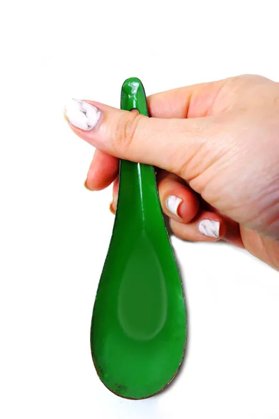 手入れされた花崗岩の女性手爪はスプーンを保持しています 白い背景の上の緑の亜鉛スプーンを閉じる — ストック写真