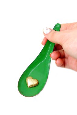 Kadın el manikürlü granit ile bir kaşık ve altın kalp tutan çiviler. Sevgililer günü yeşil çinko kaşık ve kalp sevgi kavramı üzerinde beyaz arka plan büyük herhangi bir kullanım için.