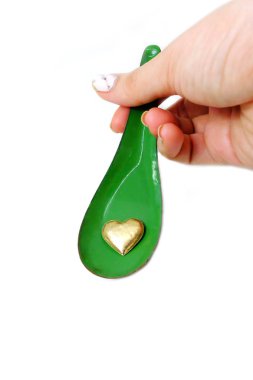 Kadın el manikürlü granit ile bir kaşık ve altın kalp tutan çiviler. Sevgililer günü yeşil çinko kaşık ve kalp sevgi kavramı üzerinde beyaz arka plan büyük herhangi bir kullanım için.