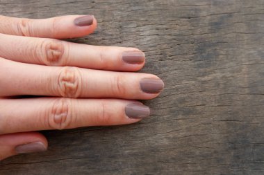 Moda kahverengi manikür çivi. Kadın el ahşap arka plan üzerinde Lehçe çivi