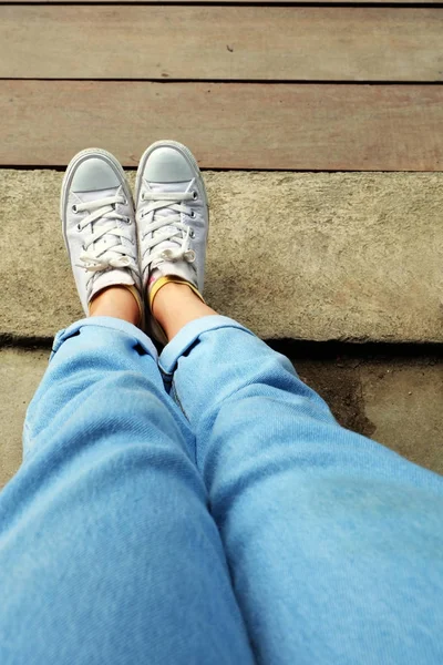 Ahşap zemin arka plan büyük herhangi bir kullanım için üzerinde Mavi Jeans ile beyaz spor ayakkabı moda kadın.