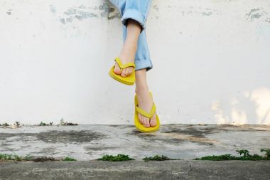 Sarı sandal. Giyen kadın Flip flop ve kot eski çimento zemin arka plan büyük üzerinde herhangi bir kullanım için ayakta.