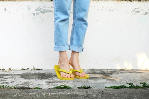 黄色凉鞋妇女穿着拖鞋和蓝色牛仔裤站在旧水泥地板背景伟大的任何使用 — 图库照片