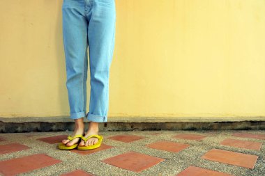 Sarı Flip flop. Sandalet ve karo döşeme arka plan büyük üzerinde herhangi bir kullanım için ayakta kot giyen erkek.