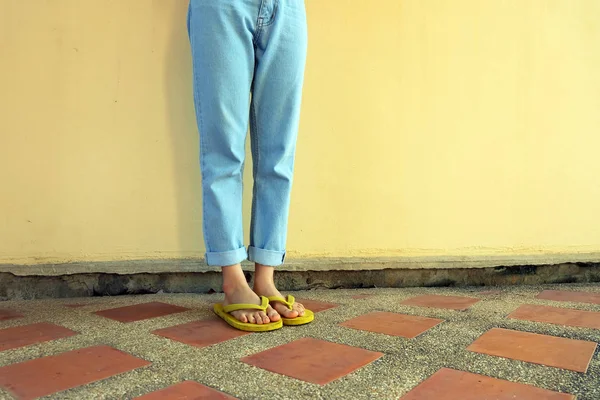 黄色的触发器 女性穿着凉鞋和蓝色牛仔裤站在瓷砖地板背景伟大的任何使用 — 图库照片