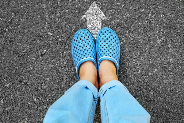 自拍蓝色的鞋子和蓝色的牛仔裤 女性脚站立与白色箭头线在道路水泥背景伟大为任何用途 — 图库照片