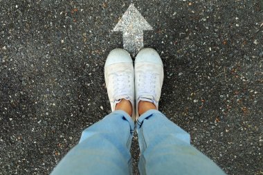 Selfie beyaz konsept ayakkabılar. Herhangi bir kullanım için beton yol arka plan büyük üstünde beyaz ok çizgi yönünü ile beyaz spor ayakkabı giyen erkek.