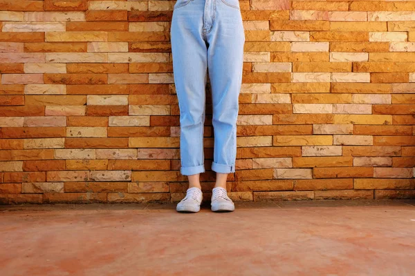 古い白い靴 女性が着る白いスニーカーとオレンジ色のレンガの壁に青いジーンズ背景任意使用のための偉大な — ストック写真