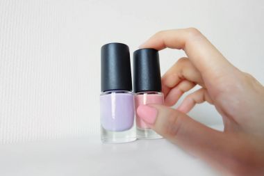 Elleri pembe boyalı çivi ile kapatın. Kadın pembe şişeyle güzel pembe tırnak manikür üzerinde beyaz arka plan büyük herhangi bir kullanım için eldir.