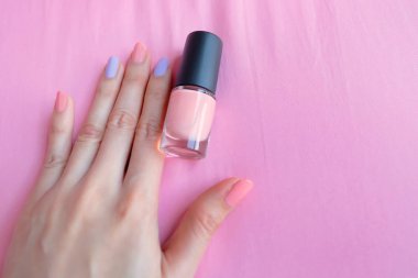 Pembe boyalı tırnaklar. Kadın pembe şişeyle güzel pembe tırnak manikür üzerinde pembe arka plan büyük herhangi bir kullanım için eldir.