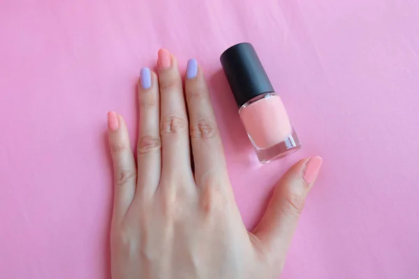 ピンク塗られた爪 女性のピンクのボトルと美しいピンクの爪マニキュアは任意の使用のために大きいピンク背景に手 — ストック写真