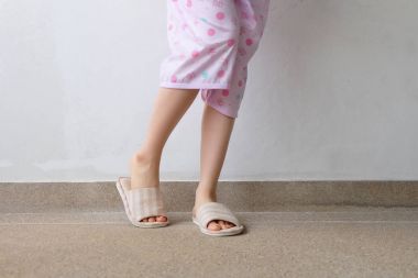 Pembe manikür çivi ile damalı sıcak terlik. Kadın bacaklar ve ayaklar pembe pijama ve terlik çimento arka plan büyük herhangi bir kullanım için üzerinde.