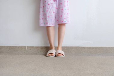 Bir çift sıcak pembe ayakkabı ile duran kadın. Pembe pijama pantolon ve üzerinde kat arka plan büyük herhangi bir kullanım için damalı terlik kadın bacakları.