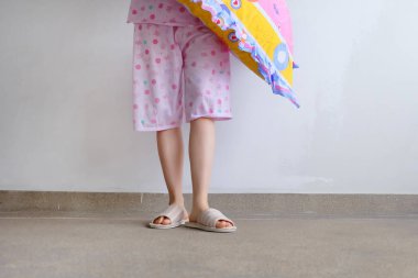 Damalı sıcak terlik. Kadın pembe pijama pantolon ve pembe yastık kat arka plan büyük üstünde tutan herhangi bir kullanım için ayakkabı.