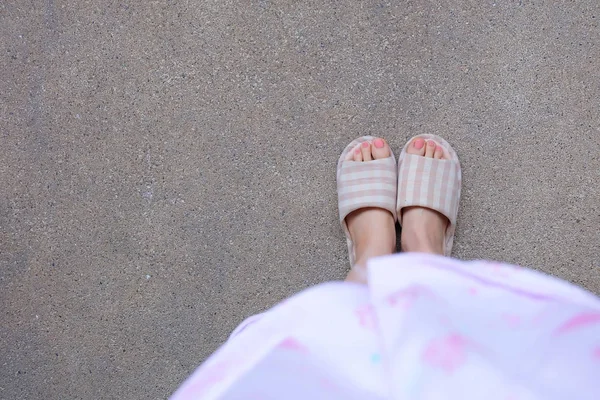 带粉红色指甲的格子保暖拖鞋 女性的腿和脚在粉红色的睡衣和拖鞋的水泥背景伟大的任何使用 — 图库照片