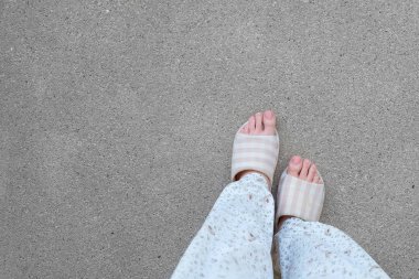 Damalı terlik üstten görünüm çifti. Kadın bacakları pijama ve çimento arka plan büyük için herhangi bir kullanım üzerinde pembe terlik (ayakkabı).
