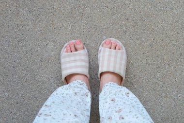 Damalı terlik üstten görünüm çifti. Kadın bacakları pijama ve çimento arka plan büyük için herhangi bir kullanım üzerinde pembe terlik (ayakkabı).