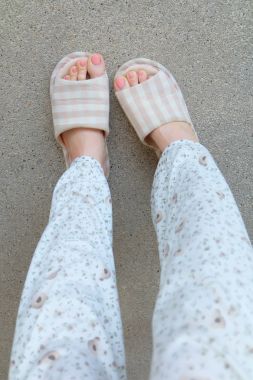 Damalı terlik üstten görünüm çifti. Kadın bacakları pijama ve çimento arka plan büyük için herhangi bir kullanım üzerinde pembe terlik (ayakkabı).