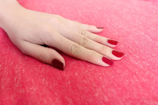 Beautiful Woman Red Nail. Female Hand with Red Nails Manicure Isolated on the Red Fabric Background Great for Any Use.