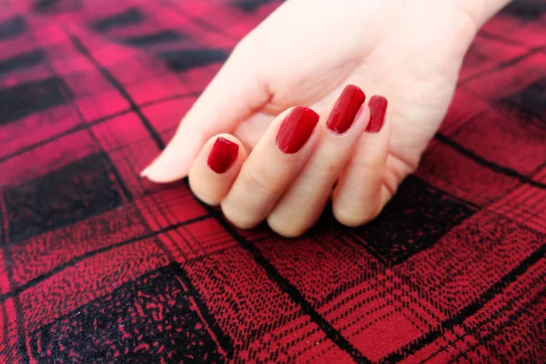 美容红色指甲指甲与凝胶抛光 妇女手与红色的指甲在红色的苏格兰布料背景伟大的任何使用 — 图库照片