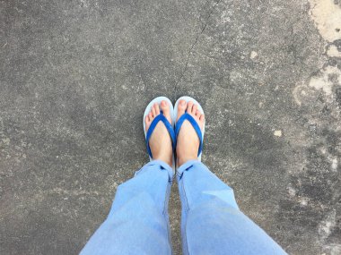 Mavi Flip Flop izole çimento zemin, üstten görünüm. Beton arka plan büyük üstünde herhangi bir kullanım için mavi ayakkabı ve Aksesuar kot giyen güzel kadın.