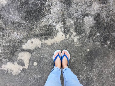 Mavi Flip Flop izole çimento zemin, üstten görünüm. Beton arka plan büyük üstünde herhangi bir kullanım için mavi ayakkabı ve Aksesuar kot giyen güzel kadın.