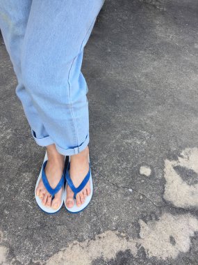 Mavi Flip Flop izole çimento zemin, üstten görünüm. Beton arka plan büyük üstünde herhangi bir kullanım için mavi ayakkabı ve Aksesuar kot giyen güzel kadın.