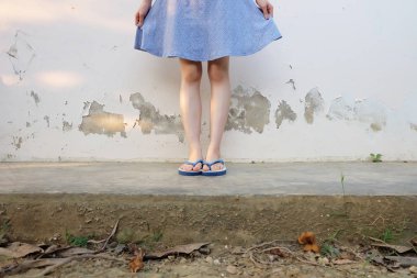 Selfie kız ince mavi ayakkabılar ve beton zemin üzerinde izole elbise bacaklar. Mavi giyen duran kadın Flop (Peep) çimento zemin arka plan büyük üzerinde herhangi bir kullanım için Flip.