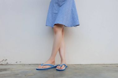 Selfie kız ince mavi ayakkabılar ve beton zemin üzerinde izole elbise bacaklar. Mavi giyen duran kadın Flop (Peep) çimento zemin arka plan büyük üzerinde herhangi bir kullanım için Flip.