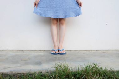 Selfie kız ince mavi ayakkabılar ve beton zemin üzerinde izole elbise bacaklar. Mavi giyen duran kadın Flop (Peep) çimento zemin arka plan büyük üzerinde herhangi bir kullanım için Flip.