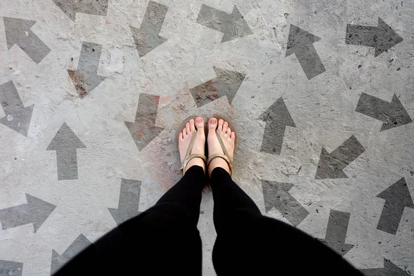 多くの方向の矢印の選択 コンクリートの床 平面図上で分離の金の靴 立っている女性は足を着てフリップフ ロップ サンダル セメント床背景偉大な任意使用のための — ストック写真